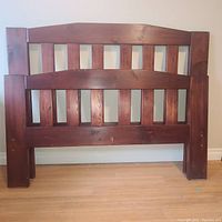 Front view of the wooden headboard and footboard with vertical slats and broad square posts.