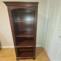 Front view of the solid cherrywood bookshelf showing multiple shelves, medium brown finish, and decorative molding at top and bottom.
