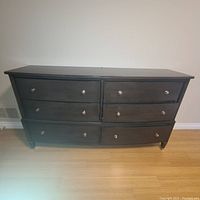 Front view of solid wood dresser with six drawers showing black finish and metal knob handles