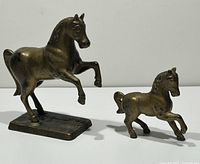 Front view of prancing horse and smaller foal still banks showing size comparison and details.