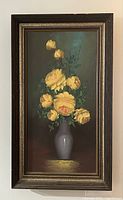 Full view of framed painting showing yellow roses in a grey vase, dark background with the signature visible.