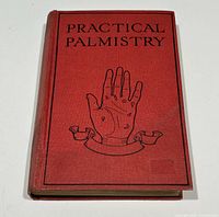 Front cover of the red hardcover book titled Practical Palmistry showing a black illustrated palm with symbols and a ribbon below the hand.