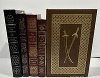 Five Easton Press leather-bound books standing upright, showing decorative and gold embossed spines.