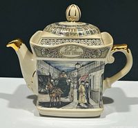 Front view of ceramic teapot showing 221B Baker Street street scene with horse carriage and figures, gold-accented handle and spout.
