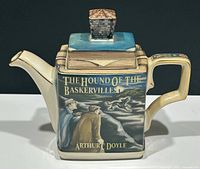Front and side view of the square teapot designed as a book with title The Hound of the Baskervilles by Arthur C. Doyle, painted with characters and dog illustration. Lid shows a blue book with tower finial.