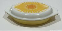 Side angle of the yellow oval divided casserole dish with white lid featuring the sunflower pattern.
