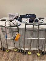 Two metal walkers with tennis balls on front legs shown alongside the air pressure pad components on a table.