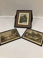 Three framed vintage prints arranged on table: two smaller town church prints and one larger grist mill print