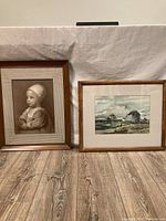 Both artworks side by side showing the sepia portrait on the left and the watercolor landscape on the right on a wooden surface