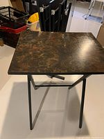 Top view showing marbled wood veneer top of one TV table with black metal legs.