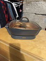 Front view of Crux electric frying pan with glass lid, showing copper interior and gray exterior