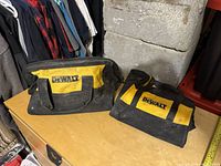 Photo showing two small DeWalt tool bags on table with black and yellow color scheme and handles.