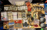 Photo showing various electrical outlets including duplex and single receptacles, wall plate covers in white, cream, and beige, wire nuts, electrical tape, and switches.