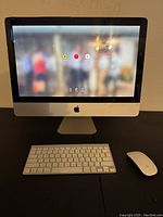 Front view of iMac with wireless keyboard and Magic Mouse powered on showing login screen