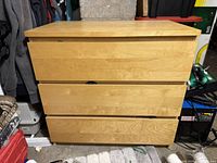 Front view of light brown wood Ikea dresser with 3 drawers.