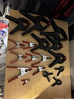 Top view of all hand clamps and spring clamps arranged on a wooden surface showing different sizes and types.