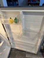 Interior door of refrigerator showing clear plastic bins with two bottle shapes for scale.