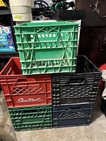 Five plastic milk crates stacked, including a red one with Sealtest branding among green, black, and blue crates.