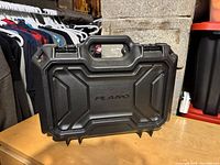 Front view of a black Plano storage box showing molded handle and contoured lid.