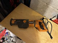Side view of the orange and black Ridgid corded reciprocating saw showing overall condition and design.