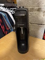 Closed SodaStream machine showing front with logo and carbonation nozzle.
