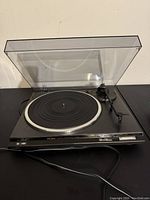 Front view of the Technics record player with open dust cover, showing platter and tonearm.