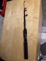 Full view of Zebco Ready Tackle collapsible fishing rod laid flat on wooden surface showing foam handle and line guides.