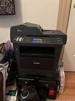 Front view of the Brother MFC multifunction printer showing keypad, display and paper output tray.