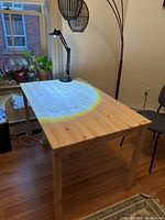 Photo of rectangular light wood IKEA table with straight legs and smooth natural finish in a well-lit living room setting.