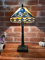 Front view of Irish stained glass lamp illuminated, showing colorful Celtic knot patterns on shade.
