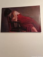Photo of a painting showing a girl in a red dress leaning on a dark wooden chair, with canvas dimensions approximately 22x32 inches.