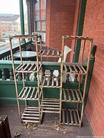 Wooden multi-tier plant stand with three columns of slatted shelves made of wood, displayed outdoors.