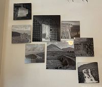 Photo of eight black and white Scotland wall art prints arranged on a wall. Includes images of castles, a barred gate, cliffs, bridges, and waterfalls.