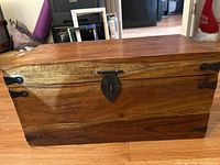 Front view of small wooden chest showing metal lock latch and corner reinforcements