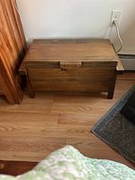 Front view of the wood toy chest showing its rectangular shape and latch.