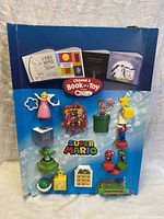 Full front photo of blue cardboard display with 11 colorful Super Mario toys and 4 children's books.