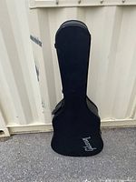 Front view of black Gibson guitar hard case standing upright, showing silver Gibson logo.