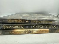 Side view of the three DVD cases stacked showing spine titles and the label indicating The Lord of the Rings trilogy from New Line Cinema.