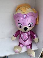 Front view of the 24 inch Skye Paw Patrol plush, showing head, face, and full body in pink pilot uniform with embroidered details and yellow fabric hairdryer.