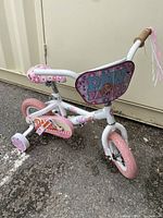 Front and side view of white and pink Paw Patrol girls bike with training wheels and pink tires needing air.