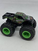 Front angled view of the Skeleton Crew Hot Wheels Monster Jam toy truck showing detailed skeleton graphics and green wheels.