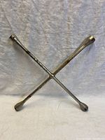 Full view of the universal lug wrench showing its cross shape and four socket heads.