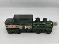 Side view of green glass train-shaped Avon collectible bottle.