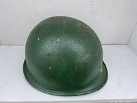 Exterior top view of vintage green military helmet showing paint wear and chips.