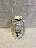 Front and side view of white metal battery operated lantern showing wear and corrosion at battery compartment.