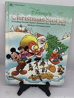 Front close-up of the vintage Disney book cover with characters Mickey Mouse, Donald Duck, Santa Claus, and Pluto in winter scene.