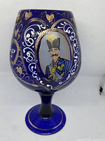 Front view of the oversized cobalt blue glass goblet with gold and white enamel designs and the enamel portrait of Qajar Dynasty man in traditional dress.