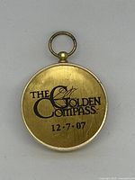 Back view of the gold-tone pocket compass with inscription 'The Golden Compass 12-7-07'.