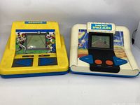 Two handheld electronic games shown side by side, one yellow and one white with blue accents, both Radio Shack games, Baseball and Space Alien