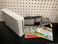 Overall front and top view of Nintendo Wii bundle with console, cords, sensor bar, and two games with cases.